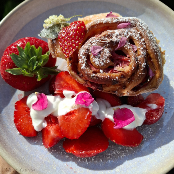 Erdbeer Rosen Holunder Schnecke auf Teller mit Erdbeeren und Rosenblüten