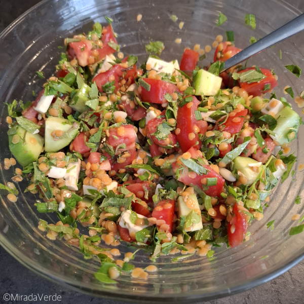 Sommerlichen Linsensalat durchmischen