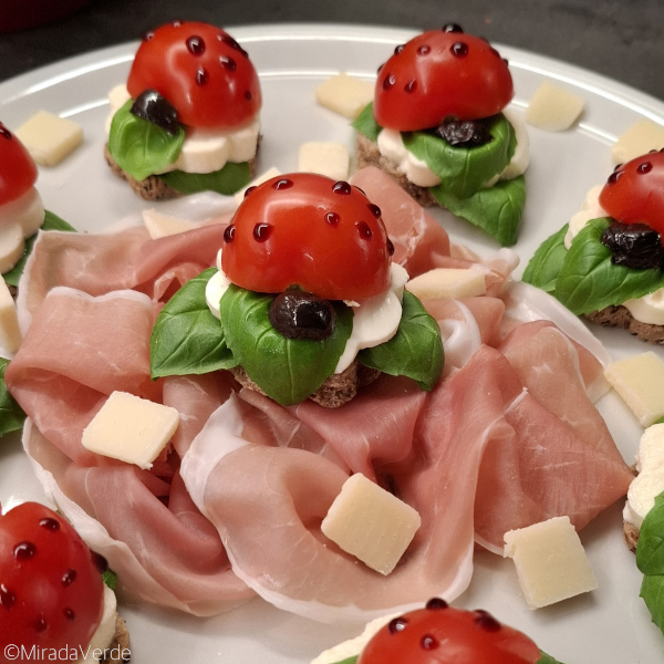 Glückskäfer Caprese mit Prosciutto und Parmesan am Teller