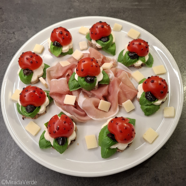 Glückskäfer Caprese mit Prosciutto und Parmesan am Teller