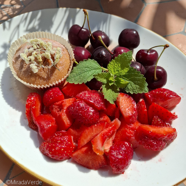 Holunderblütenmuffin mit kandierter Holunderblüte auf Erdbeeren und Kirschen, Zitronenmelisse